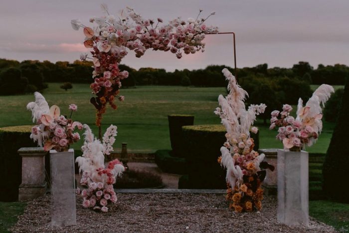 Hosting a micro wedding: Image of ceremony arch with bohemian style flowers